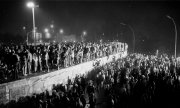Menschen klettern am 9. November 1989 in ausgelassener Feierlaune auf die Mauer. (© picture-alliance/dpa)
