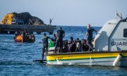 Итальянские пограничники наблюдают за прибытием лодки с мигрантами к берегам Лампедузы. (© picture-alliance/Photoshot)
