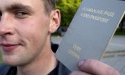 A man holding the grey passport of Estonian "non-citizens". (© picture-alliance/dpa)