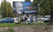 Des membres du parti d’opposition Együtt devant l’une des affiches d’une campagne du gouvernement contre Soros. (© picture-alliance/dpa)