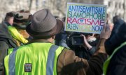 Ein Demonstrant hält ein Schild mit der Aufschrift: Antisemitismus, Islamophobie, Rassismus - nicht in unserem Namen. (© picture-alliance/dpa)