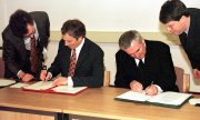 1998 год: премьер-министр Великобритании Тони Блэр (слева) и премьер-министр (Тишек) Ирландии Берти Ахерн ставят свои подписи под текстом Белфастского соглашения. (© picture-alliance/dpa)