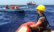 Refugees await the arrival of a rescue boat of the organisation Sea-Eye off Lampedusa. (© picture-alliance/dpa)