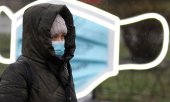 Passerby in front of a face mask sculpture in Kiev. (© picture-alliance/dpa)