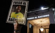 A demonstrator holds up a poster reading "Fire against racism". (© picture alliance / EPA / Isaac Fontana)
