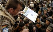 A German soldier distributes newspapers among locals in the Afghan city of Taloqan in November 2004. (© picture-alliance/ ZB/Peter Endig)