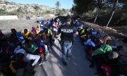 A police officer surrounded by refugees on Lampedusa. (© picture-alliance/ZUMAPRESS.com/Ciro Fusco)