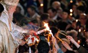 Der rumänische Patriarch Theoktist (1915-2007) verteilt das "heilige Feuer" an Gläubige. (© picture-alliance/dpa)