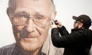 A visitor to the Ikea museum in Almhult in front of a portrait of Kamprad. (© picture-alliance/dpa)
