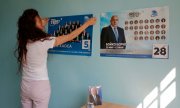 Eine Frau hängt Plakate von Ex-Premier Borissows Partei Gerb auf. (© picture-alliance/Valentina Petrova)