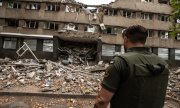 Украинский солдат перед разрушенным зданием в Николаеве, 17 июля 2022 года. (© picture-alliance/ZUMAPRESS.com/Гектор Адольфо Квантанар Перес)