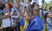Nach dem Gefangenenaustausch: Menschen zeigen ukrainischen Soldaten Fotos von vermissten Angehörigen. (© picture alliance/ASSOCIATED PRESS/Efrem Lukatsky)