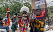 Женщины несут посылки с гуманитарной помощью, Кения, июль 2022 года. (© picture-alliance/Associated Press/Десмонд Тиро)