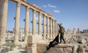 Ein syrischer Soldat entfernt eine Flagge der IS-Miliz aus Palmyra. (© picture-alliance/dpa)