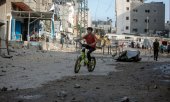 Ein Junge fährt auf seinem Fahrrad durch ein beschädigtes Wohngebiet im Gazastreifen. (© picture-alliance/Khalil Hamra)