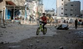 A boy riding his bicycle through a devastated residential area in the Gaza Strip. (© picture-alliance/Khalil Hamra)