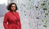 Oslo's Deputy Mayor Kamzy Gunaratnam on 9 July standing next to a memorial with the names of the victims who, unlike her, did not survive the attack. (© picture-alliance/Sigrid Harms)