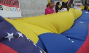 Opposition demonstrators holding a Venezuelan flag. (© picture-alliance/dpa)