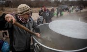 A volunteer cooks soup for refugees arriving at Medyka railway station in Poland. (© picture alliance/ASSOCIATED PRESS/Visar Kryeziu)