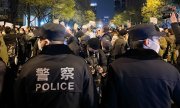 27 Kasım 2022'de Pekin'de polis gözetimi altında düzenlenen bir gösteri. (© picture alliance/dpa/TASS/Stringer)