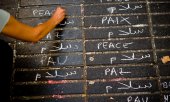 A woman writing "peace" in various languages in Barcelona. (© picture-alliance/dpa)