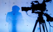 Angela Merkel's shadow in front of a television camera. (© picture-alliance/dpa)