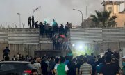 Protesters scale the wall of the Swedish embassy in Baghdad. (© picture alliance / ASSOCIATED PRESS / Ali Jabar)