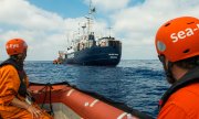 Два сотрудника морской поисково-спасательной службы смотрят на спасательный корабль Алан Курди. (© picture-alliance/dpa)