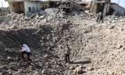 Men standing among destroyed houses in Idlib on 22 August 2019. (© picture-alliance/dpa)