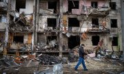 25 Şubat 2022'de Kiev'deki yıkılan bir binanın önünden geçen bir yaya. (© picture alliance / ASSOCIATED PRESS / Emilio Morenatti)